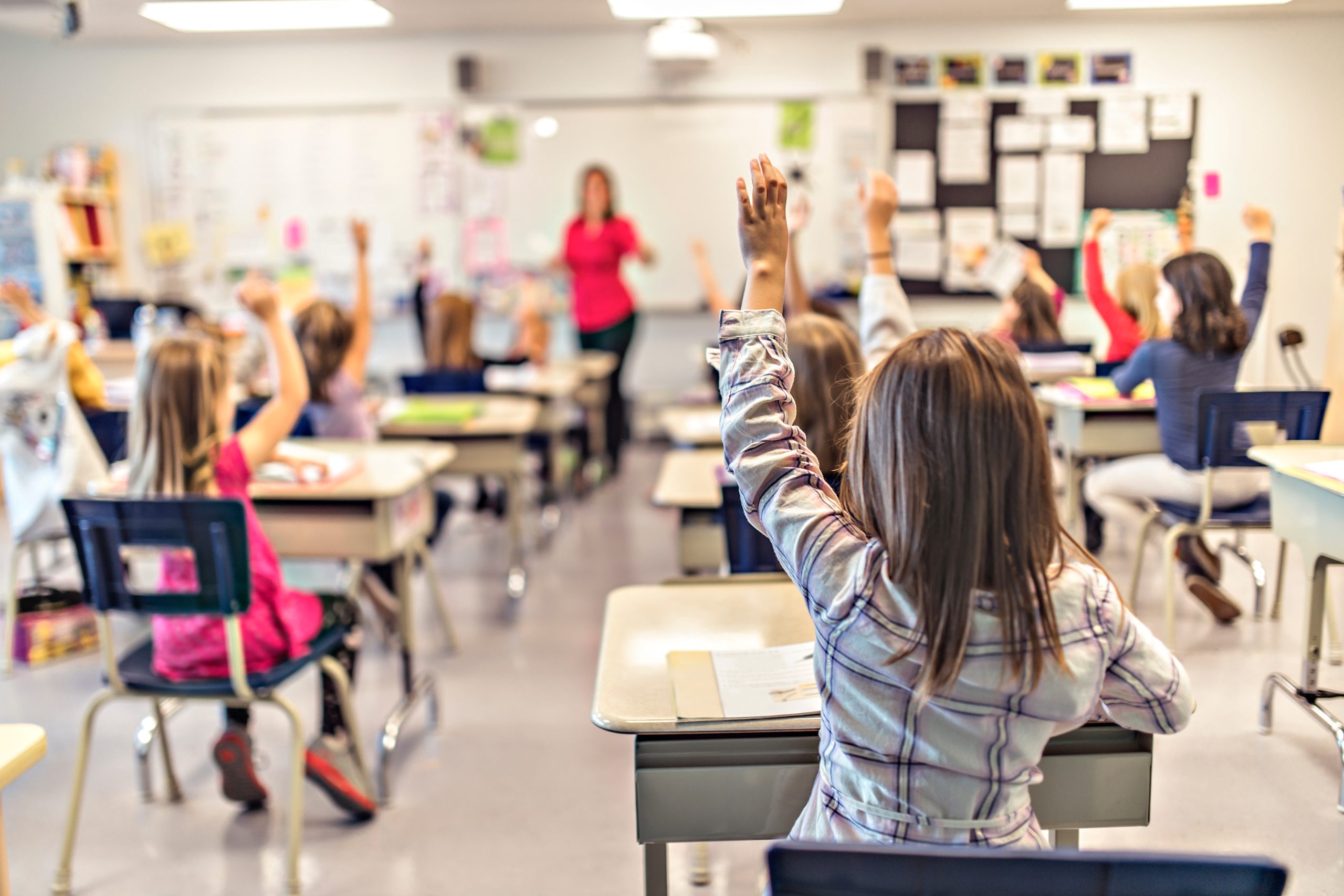 Fille levant sa main en classe a l'école